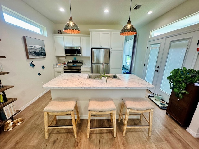 12077 Lakeshore Way, Oxford, FL 34484 - kitchen featuring stainless steel appliances, light wood-type flooring, white cabinets, a kitchen breakfast bar, and recessed lighting