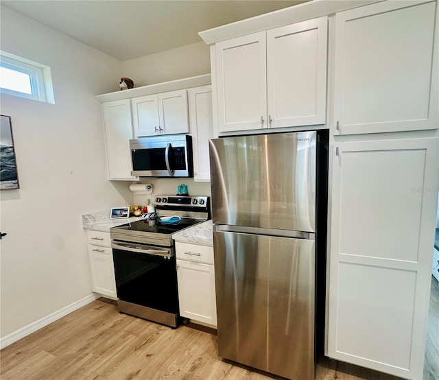 12077 Lakeshore Way, Oxford, FL 34484 - kitchen featuring appliances with stainless steel finishes, light wood finished floors, white cabinets, baseboards, and light stone countertops