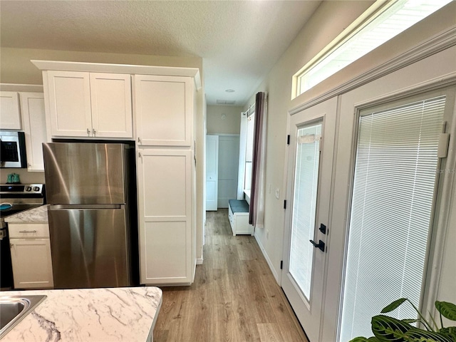 12077 Lakeshore Way, Oxford, FL 34484 - kitchen with stainless steel appliances, light wood-type flooring, white cabinetry, and light countertops