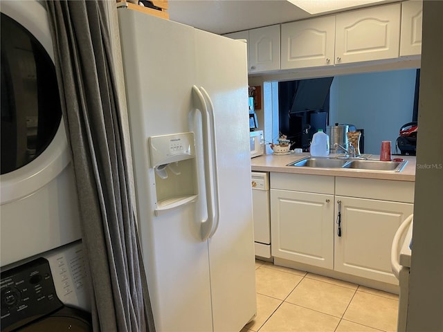 206 Orchid Dr, Davenport, FL 33897 - kitchen with stacked washer / dryer, white appliances, light tile patterned floors, white cabinets, and a sink
