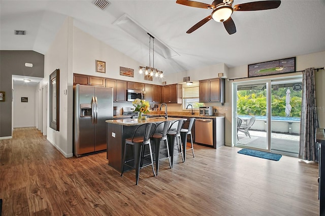 1204 Monterey Dr, Eustis, FL 32726 - kitchen featuring appliances with stainless steel finishes, vaulted ceiling, a ceiling fan, a breakfast bar, and a kitchen island with sink