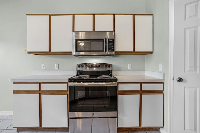 2711 Bayview Dr, Eustis, FL 32726 - kitchen with stainless steel appliances, light countertops, white cabinets, baseboards, and light tile patterned flooring