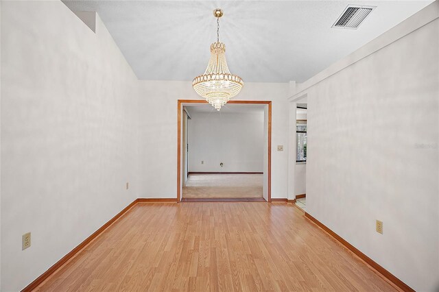 501 Cherry Tree St, Eustis, FL 32726 - empty room with a chandelier, light wood finished floors, and baseboards