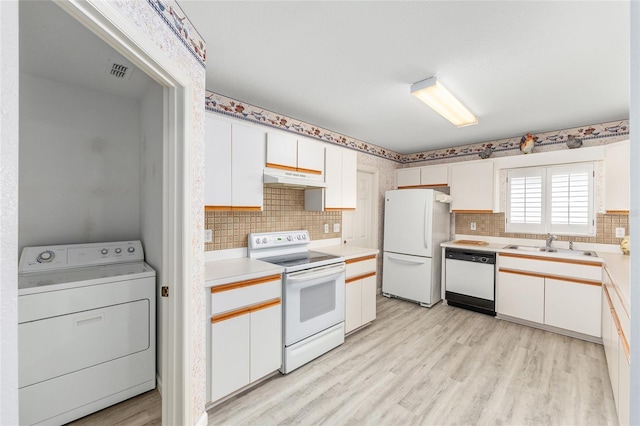 8608 SE 141st Street Rd, Summerfield, FL 34491 - kitchen featuring washer / dryer, white appliances, under cabinet range hood, light wood-type flooring, and white cabinetry