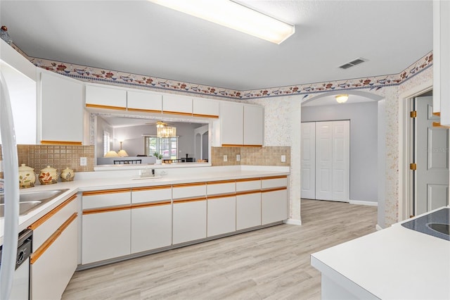 8608 SE 141st Street Rd, Summerfield, FL 34491 - kitchen with wallpapered walls, light countertops, backsplash, light wood finished floors, and arched walkways