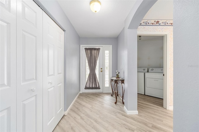 8608 SE 141st Street Rd, Summerfield, FL 34491 - foyer entrance with washing machine and clothes dryer, light wood-style floors, arched walkways, and baseboards