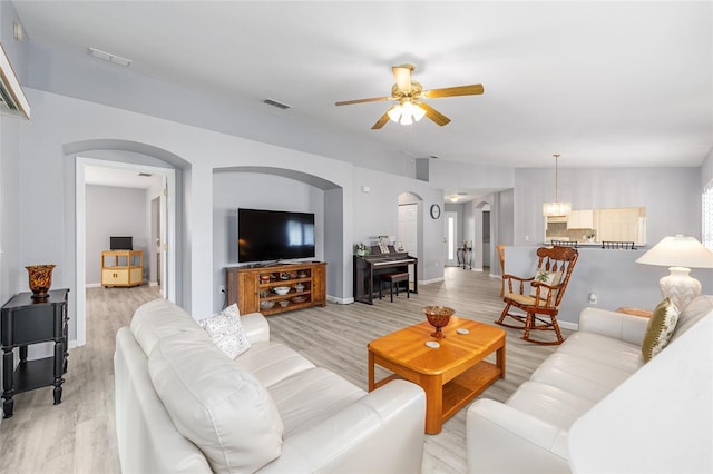 8608 SE 141st Street Rd, Summerfield, FL 34491 - living room with arched walkways, light wood-style floors, a ceiling fan, and baseboards