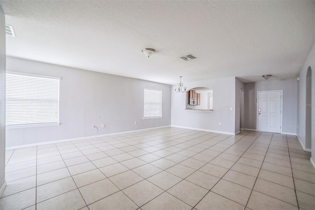236 Savannah Preserve Loop, Davenport, FL 33837 - empty room with a chandelier, light tile patterned floors, a textured ceiling, baseboards, and arched walkways