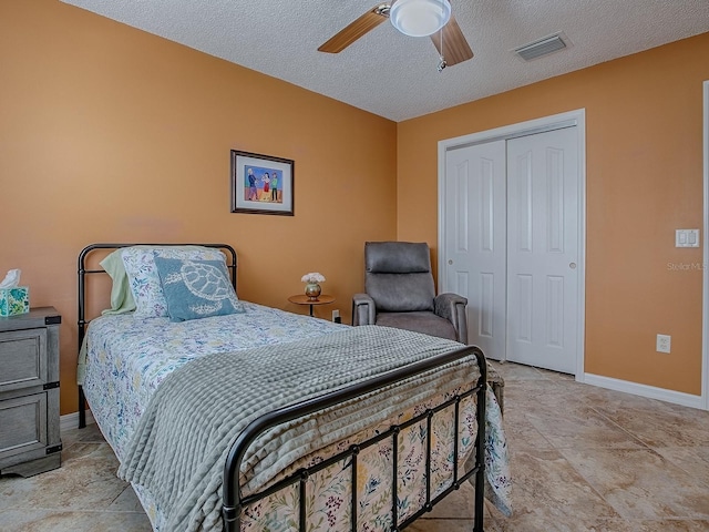 1206 Thompson Ave, The Villages, FL 32162 - bedroom with a closet, baseboards, a ceiling fan, stone finish floors, and a textured ceiling