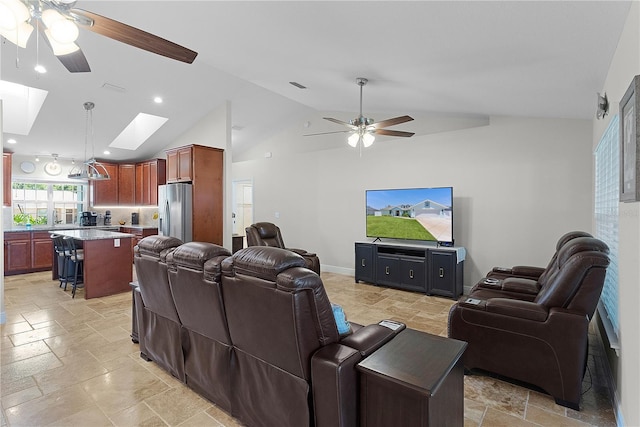 living room with ceiling fan, stone tile floors, a skylight, high vaulted ceiling, and recessed lighting