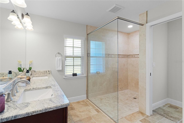 full bath with a chandelier, a walk in shower, baseboards, stone finish floors, and double vanity