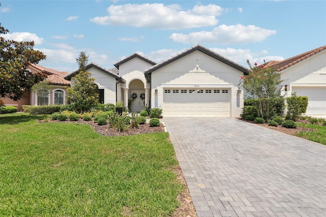 9307 San Jose Blvd, Howey In The Hills, FL 34737 - view of front of house with stucco siding, decorative driveway, a front yard, an attached garage, and a tile roof
