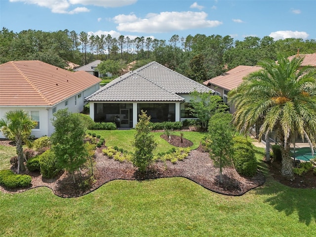 9307 San Jose Blvd, Howey In The Hills, FL 34737 - rear view of property featuring a tiled roof, a sunroom, a lawn, and stucco siding