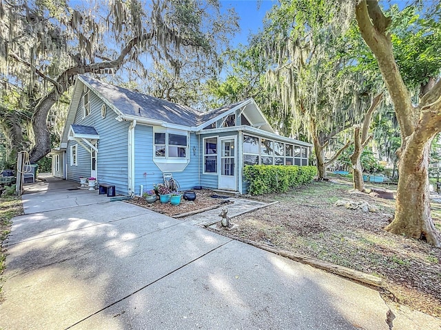 1107 Northshore Dr, Eustis, FL 32726 - view of front of house with a sunroom, driveway, and roof with shingles