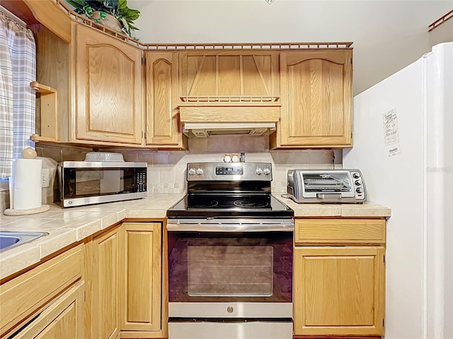 1107 Northshore Dr, Eustis, FL 32726 - kitchen featuring appliances with stainless steel finishes, tile countertops, light brown cabinetry, and decorative backsplash