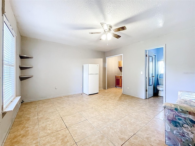 1107 Northshore Dr, Eustis, FL 32726 - unfurnished bedroom with freestanding refrigerator, light tile patterned floors, ensuite bath, a textured ceiling, and baseboards