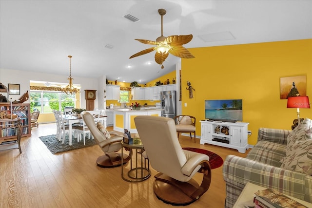 living room with lofted ceiling, light wood-type flooring, ceiling fan, and a chandelier