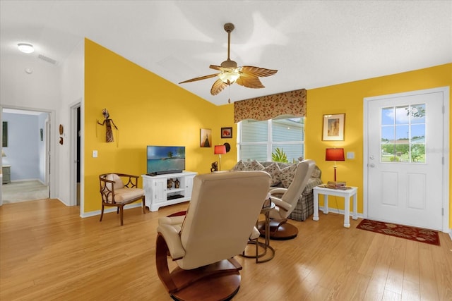 living room with light wood-type flooring, lofted ceiling, ceiling fan, and baseboards
