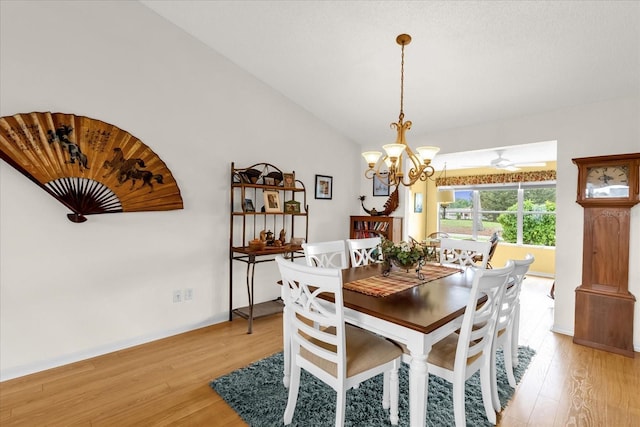 dining space featuring light wood-type flooring, a chandelier, vaulted ceiling, and baseboards
