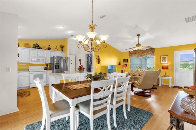 dining space with light wood-style floors, a ceiling fan, a chandelier, and lofted ceiling
