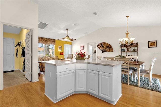 kitchen with vaulted ceiling, light wood-style floors, a chandelier, white cabinets, and a center island