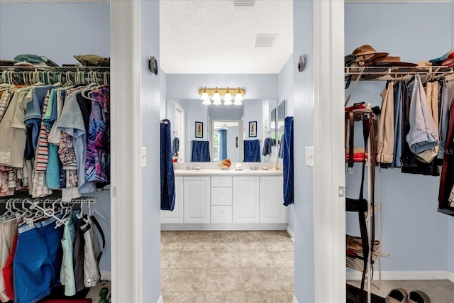 full bath featuring double vanity, a spacious closet, and baseboards