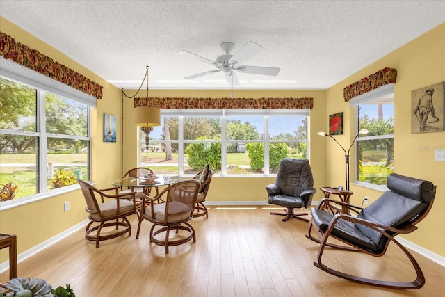 sunroom featuring a textured ceiling, healthy amount of natural light, baseboards, and wood finished floors