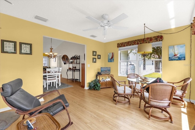 living room with light wood-type flooring, baseboards, a chandelier, and ceiling fan