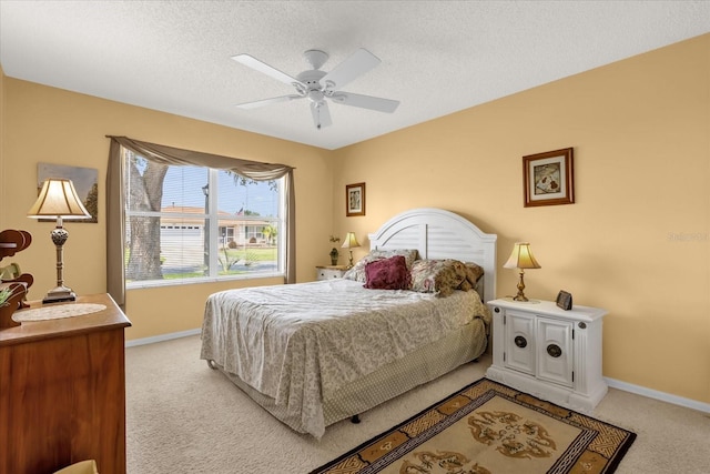 bedroom featuring light carpet, baseboards, a textured ceiling, and ceiling fan