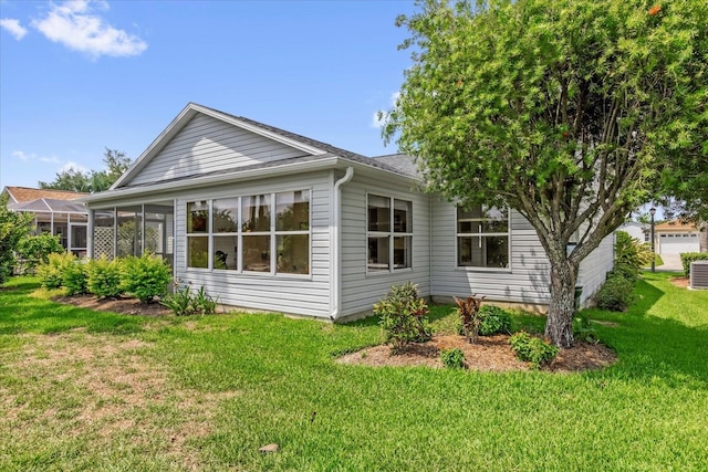 view of home's exterior featuring a lawn, a sunroom, and roof with shingles