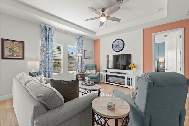2928 Marlberry Ln, Clermont, FL 34714 - living room featuring a tray ceiling, light wood-style floors, ceiling fan, and baseboards
