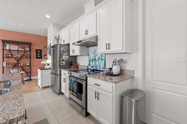 2928 Marlberry Ln, Clermont, FL 34714 - kitchen with under cabinet range hood, appliances with stainless steel finishes, white cabinets, light stone countertops, and light tile patterned floors