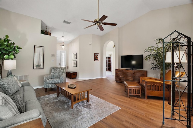 25406 Crestwater Dr, Leesburg, FL 34748 - living room with vaulted ceiling, arched walkways, ceiling fan, light wood-style floors, and baseboards