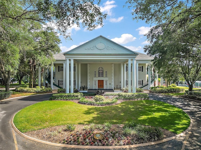 25406 Crestwater Dr, Leesburg, FL 34748 - greek revival inspired property featuring a porch, a front lawn, curved driveway, and stucco siding