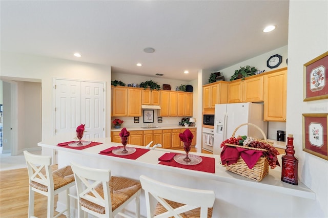 13165 SE 93rd Cir, Summerfield, FL 34491 - kitchen featuring white appliances, a kitchen breakfast bar, light countertops, light brown cabinets, and recessed lighting