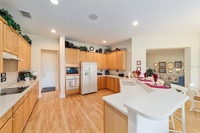 13165 SE 93rd Cir, Summerfield, FL 34491 - kitchen featuring black appliances, a peninsula, light brown cabinets, a breakfast bar, and a sink