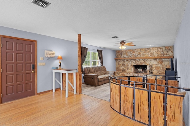 5581 SW 197th Ter, Dunnellon, FL 34431 - living room featuring a textured ceiling, hardwood / wood-style floors, ceiling fan, and a fireplace