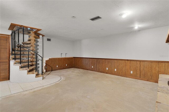 5581 SW 197th Ter, Dunnellon, FL 34431 - spare room featuring concrete floors, stairs, wooden walls, and a wainscoted wall
