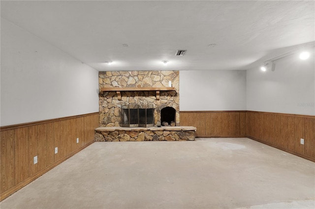 5581 SW 197th Ter, Dunnellon, FL 34431 - unfurnished living room with a wainscoted wall, wood walls, a stone fireplace, and concrete floors