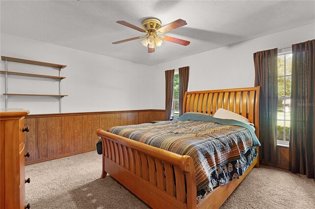 5581 SW 197th Ter, Dunnellon, FL 34431 - bedroom featuring multiple windows, wainscoting, light carpet, wooden walls, and a ceiling fan