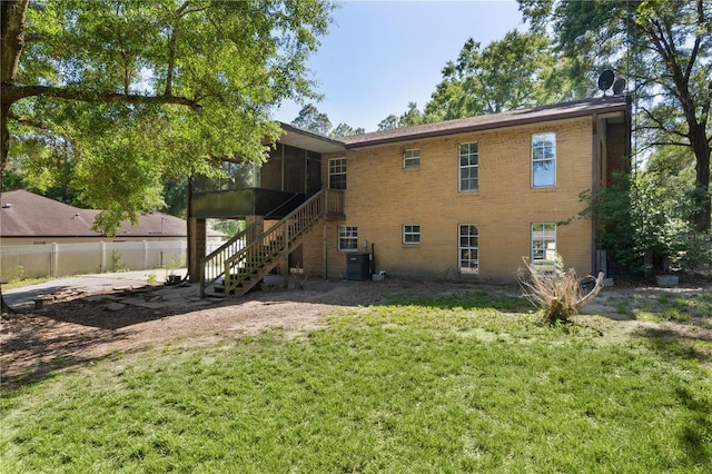 5581 SW 197th Ter, Dunnellon, FL 34431 - rear view of property featuring a sunroom, stairway, brick siding, and central AC unit