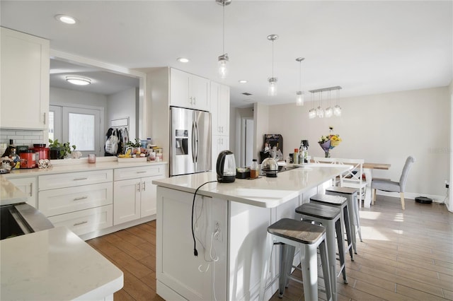 1226 Overlook Rd, Eustis, FL 32726 - kitchen with stainless steel fridge, a breakfast bar area, light countertops, white cabinets, and recessed lighting