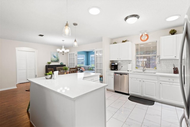 612 Lisbon Ln, The Villages, FL 32159 - kitchen with appliances with stainless steel finishes, a chandelier, decorative backsplash, light countertops, and a sink
