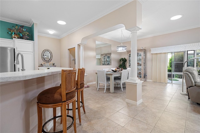 8980 SE 176th Limerick Ln, The Villages, FL 32162 - kitchen featuring decorative columns, freestanding refrigerator, crown molding, and a breakfast bar area