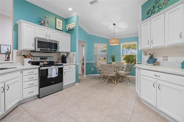 8980 SE 176th Limerick Ln, The Villages, FL 32162 - kitchen featuring appliances with stainless steel finishes, crown molding, light tile patterned flooring, light countertops, and white cabinetry
