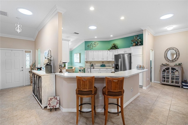 8980 SE 176th Limerick Ln, The Villages, FL 32162 - kitchen with stainless steel refrigerator with ice dispenser, ornamental molding, white cabinetry, healthy amount of natural light, and light countertops