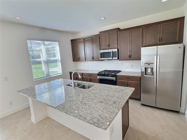 358 Switchgrass Loop, Minneola, FL 34715 - kitchen with appliances with stainless steel finishes, a sink, dark brown cabinetry, light stone counters, and a kitchen island with sink