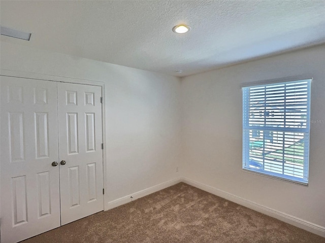 358 Switchgrass Loop, Minneola, FL 34715 - unfurnished bedroom with dark colored carpet, a textured ceiling, baseboards, and a closet