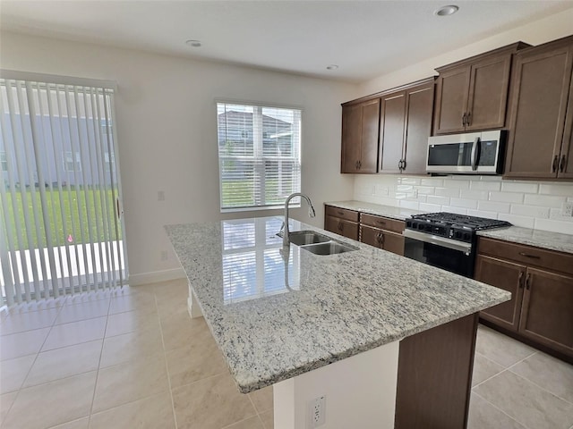 358 Switchgrass Loop, Minneola, FL 34715 - kitchen with stainless steel microwave, gas stove, a sink, a center island with sink, and light stone counters