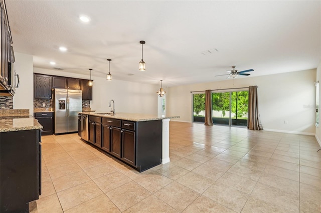 185 Hamlet Loop, Davenport, FL 33837 - kitchen with stainless steel appliances, light tile patterned floors, open floor plan, backsplash, and dark brown cabinetry